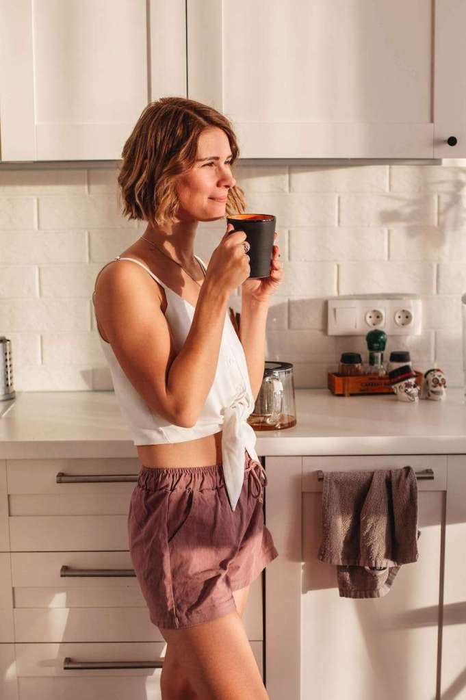 happy woman drinking coffee in kitchen: virtual homeschool mom retreat