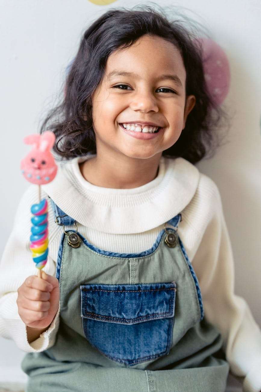 cheerful hispanic girl with lollipop during easter celebration