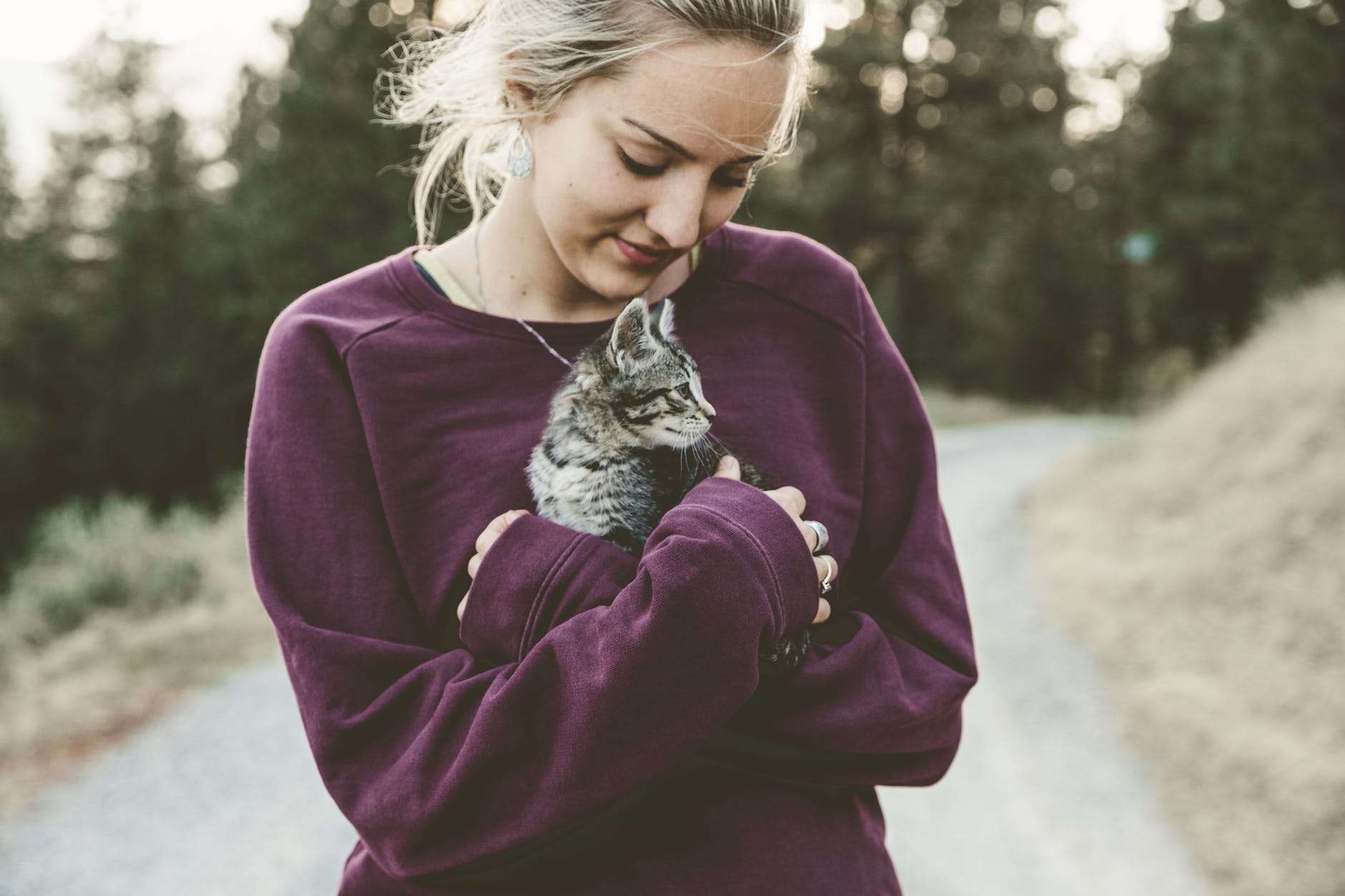 selective focus photography of woman wearing purple sweater holding silver tabby cat: a realistic self-care checklist