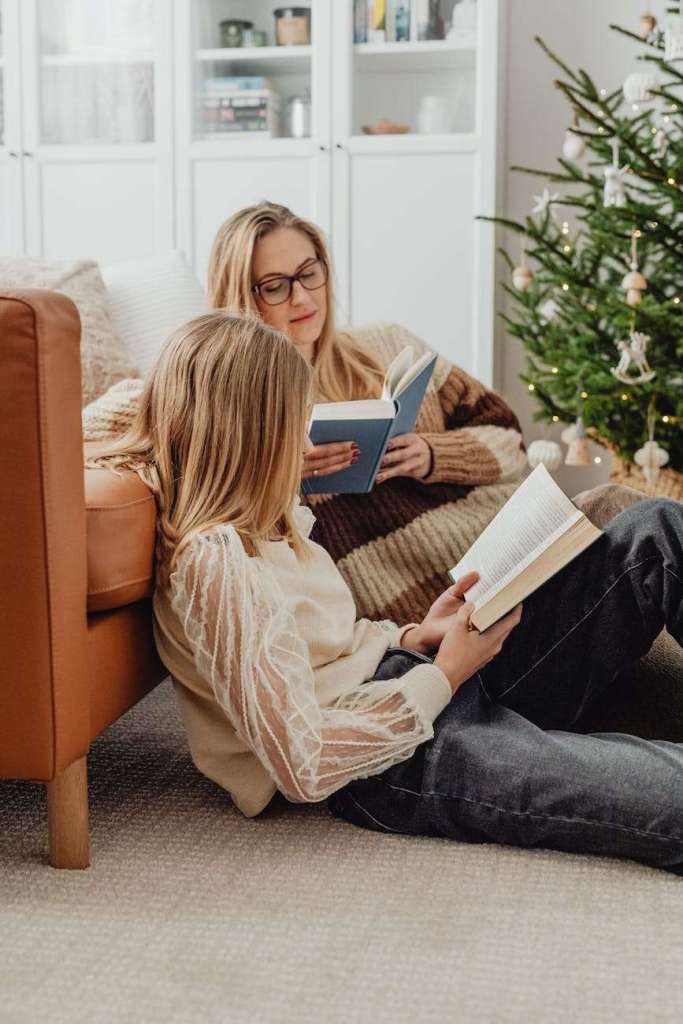 mother and daughter reading books in a living room at christmas: Here is a simple guide to unschooling your holiday homeschool  