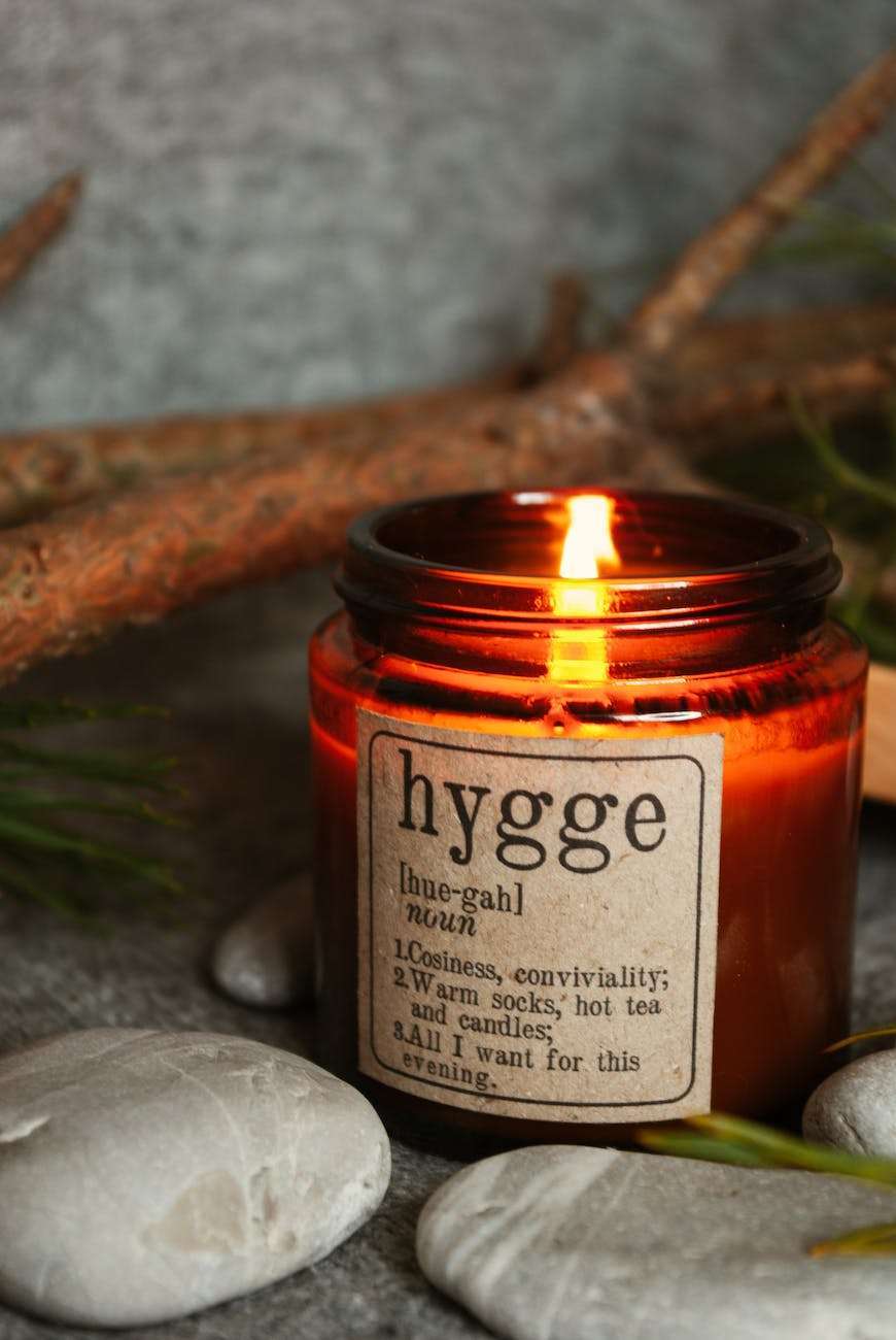 burning aromatic candle with stone and tree branches on table: Homeschool Hygge Checklist
