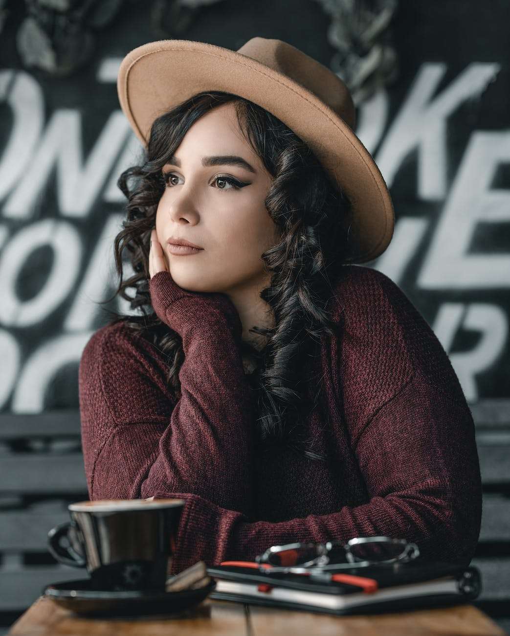 woman wearing brown hat leaning on wooden table