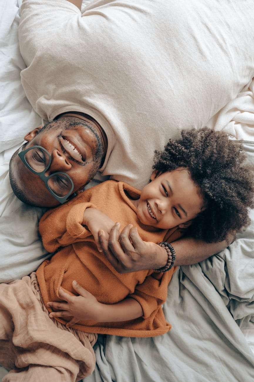candid black man and kid on bed