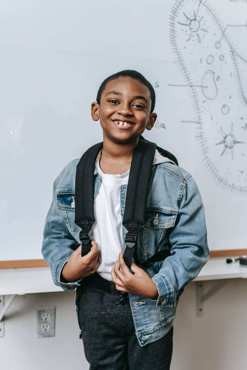cheerful black kid standing near whiteboard in classroom feeling confident: develop boundaries in my homeschool life to enable confident kids