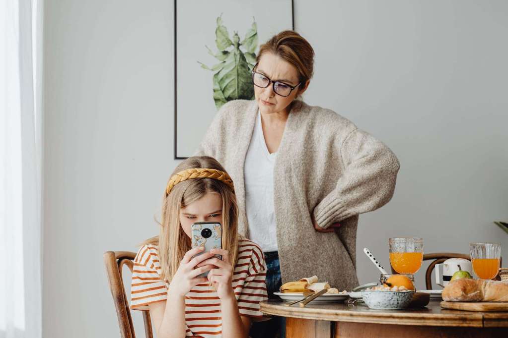 woman frustrated about her daughter using mobile phone during breakfast