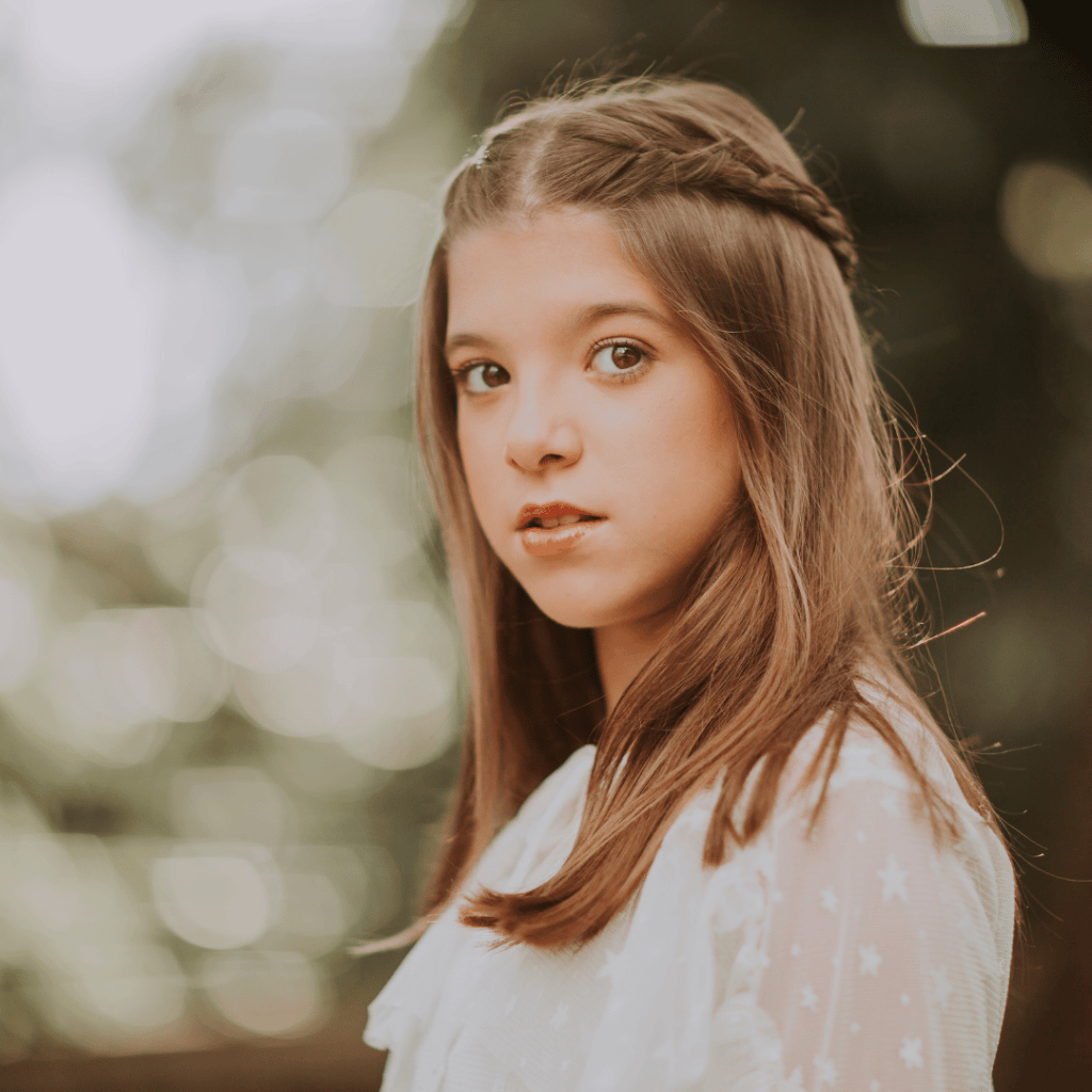 A young girl with a braided hairstyle looking over her shoulder with a soft, curious expression — representing a child whose unique learning style deserves to be seen and honored