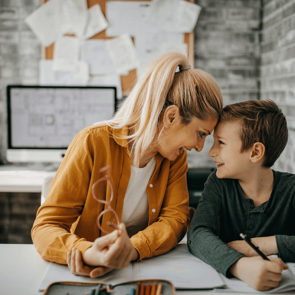 Homeschool mom sharing a joyful moment with her son during a lesson — the leadership and communication skills of entrepreneurship, built one day at a time