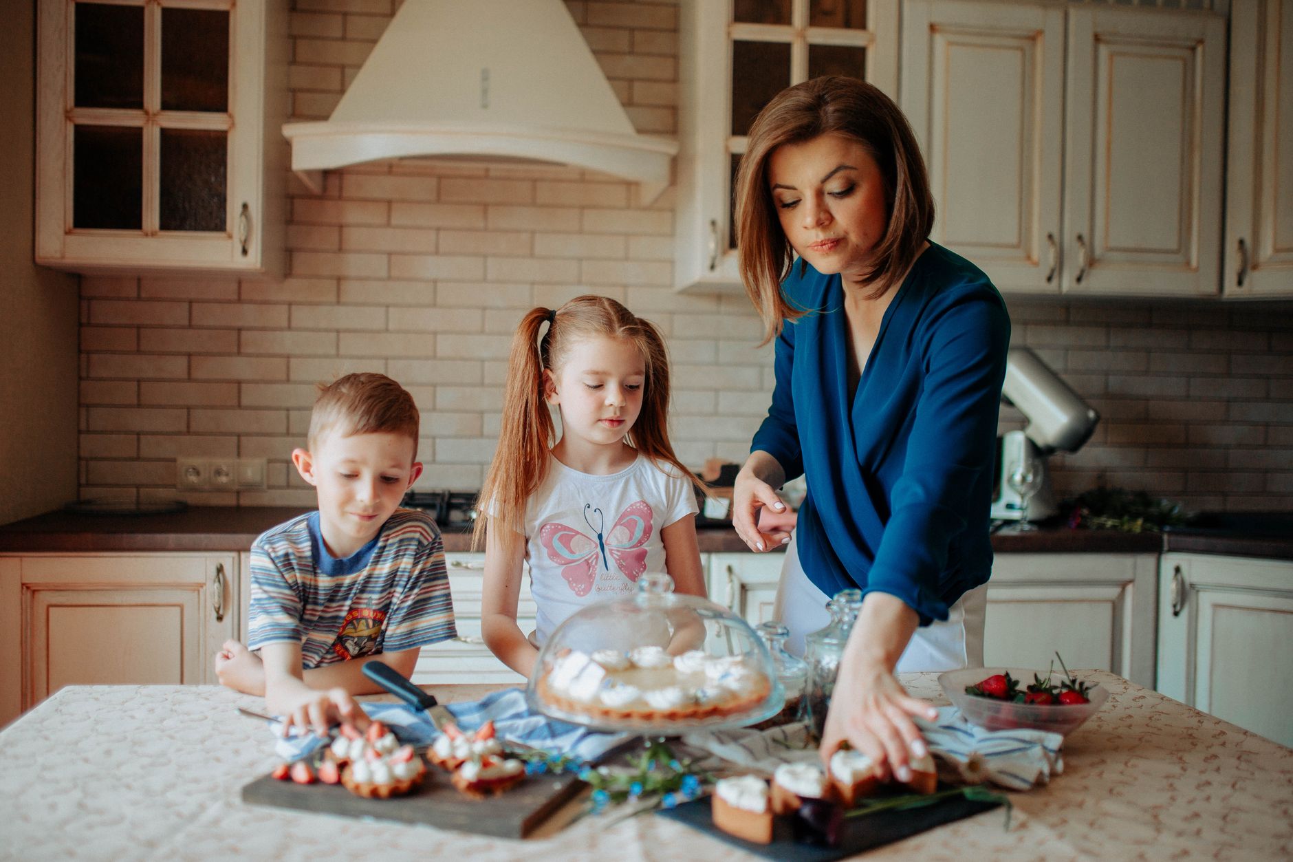 kids with mom near counter with different desserts in kitchen